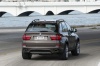 Driving 2013 BMW X5 xDrive50i in Sparkling Bronze Metallic from a rear right view